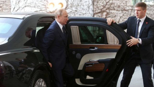 Vladimir Putin gets out of the car with his bodyguard.