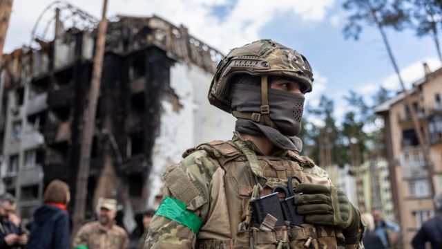 Ukrainian soldier in front of a destroyed building